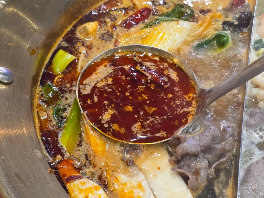 Adding vegetables and toppings into the boiling half-and-half broth