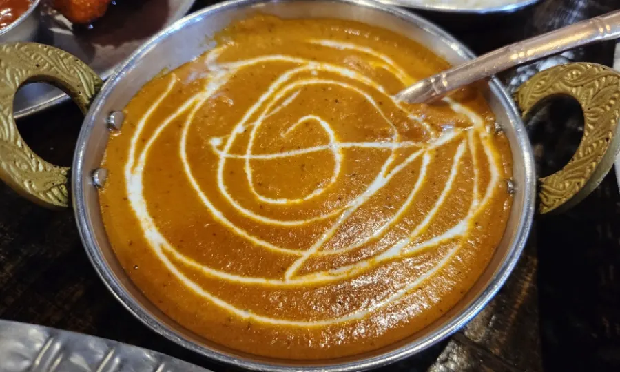 Table with butter chicken curry and naan