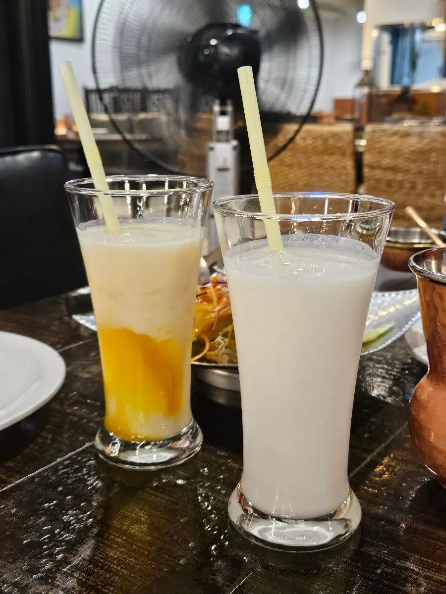 Two glasses of plain lassi and mango lassi