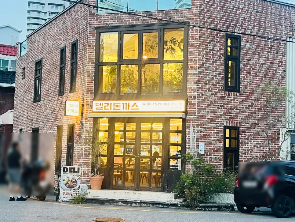 Deli Donkatsu exterior with big window lit up in the evening
