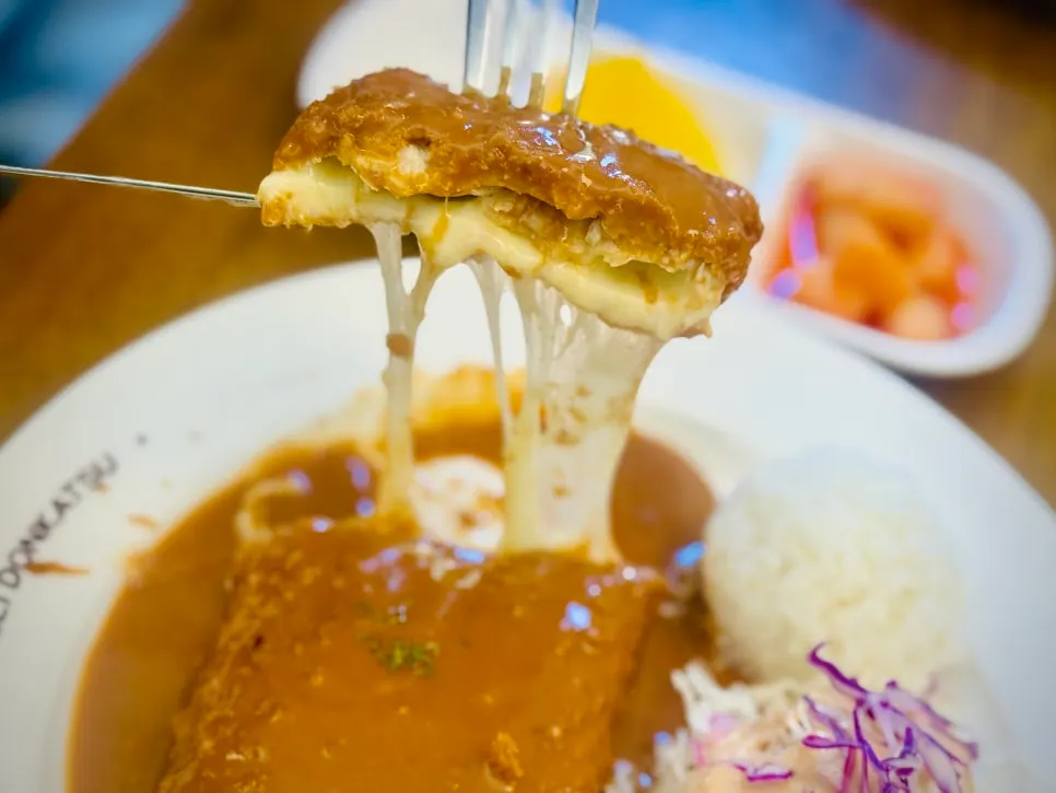 Cheese pork cutlet lifted up to show the cheese pull