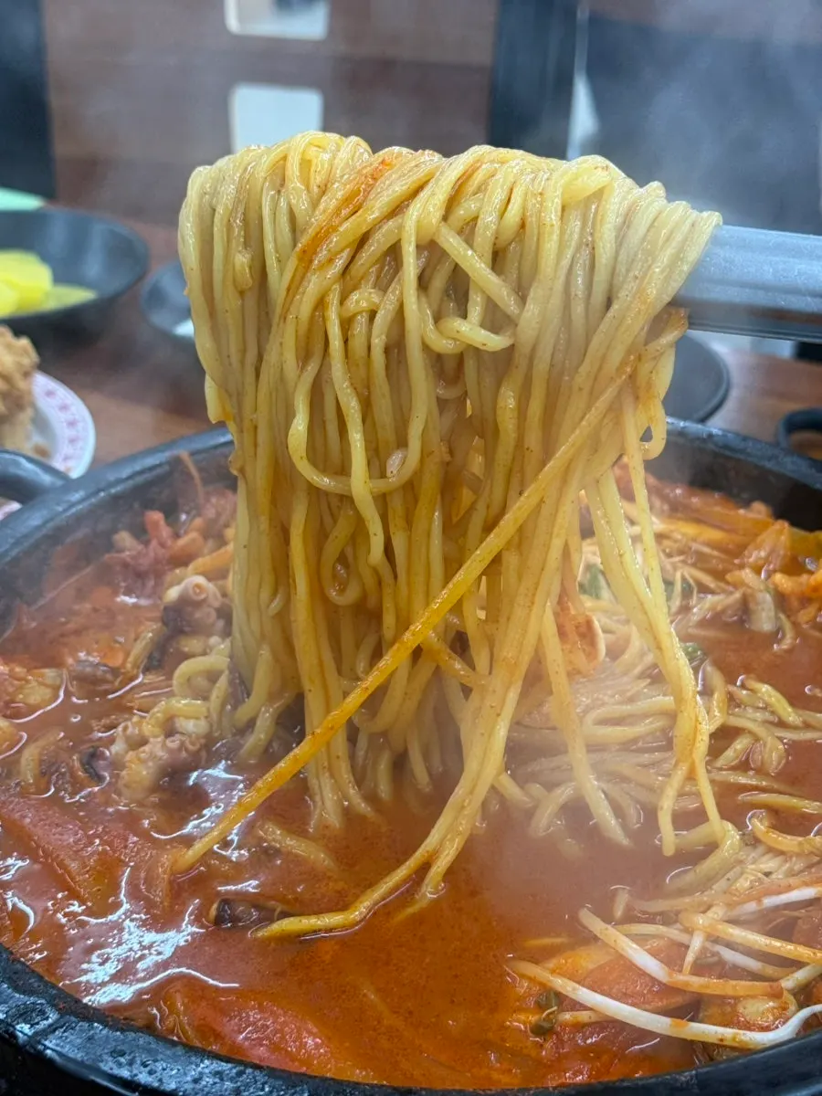 Chopstick-full of dol jjamppong noodles loaded with bean sprouts