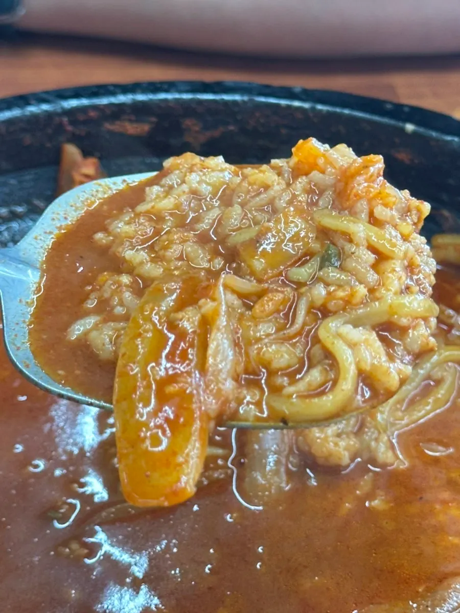 Scraping the scorched rice off the bottom of the stone plate with a spatula