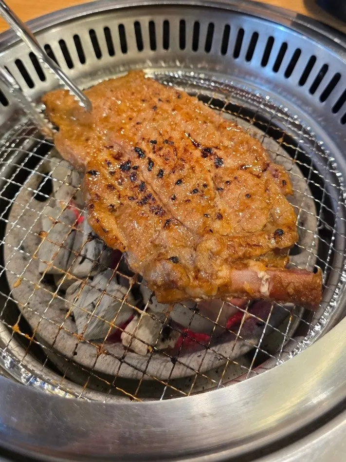 Seasoned pork galbi grilling over charcoal