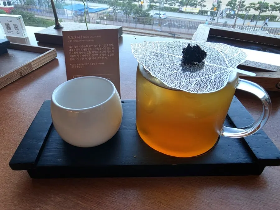 Iced tea topped with tea leaves alongside a tea description card