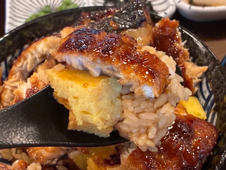 Eel sliced with a rice paddle next to a thick egg layer