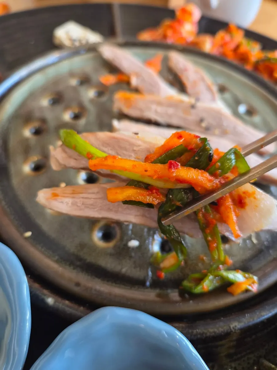 Dipping bean sprouts and enoki mushrooms into the sauce
