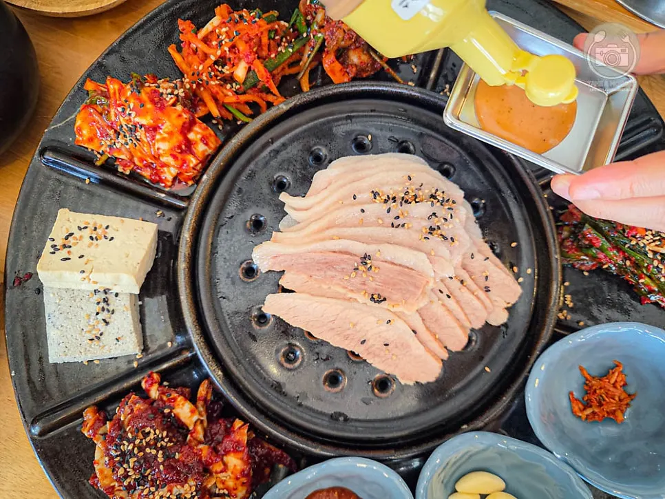 Bossam and a dozen side dishes arranged on a round plate