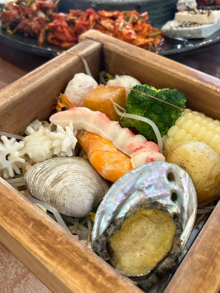 Seafood hinoki steam box topped with abalone, shrimp and clams