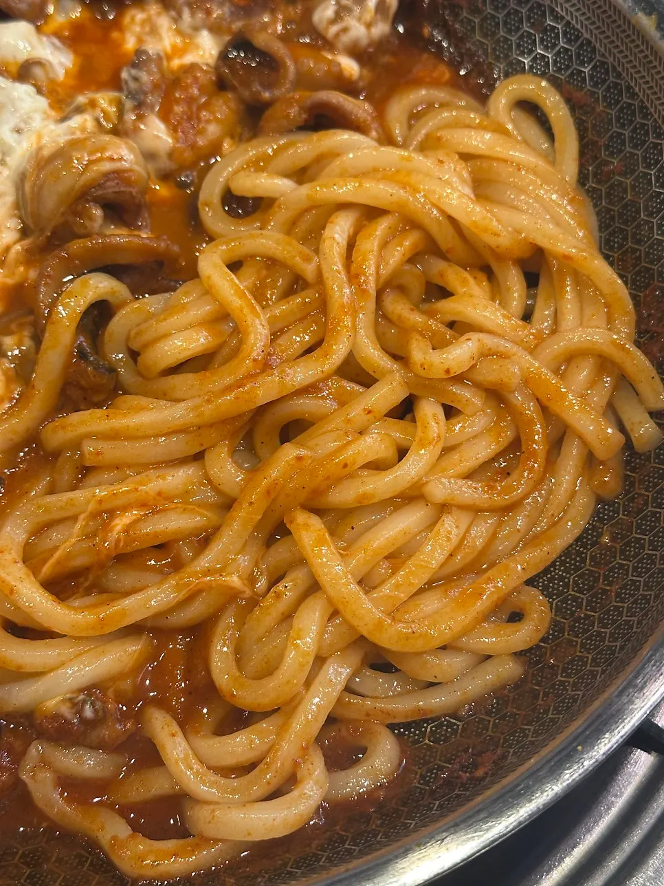 Udon noodles added into the octopus sauce on the griddle