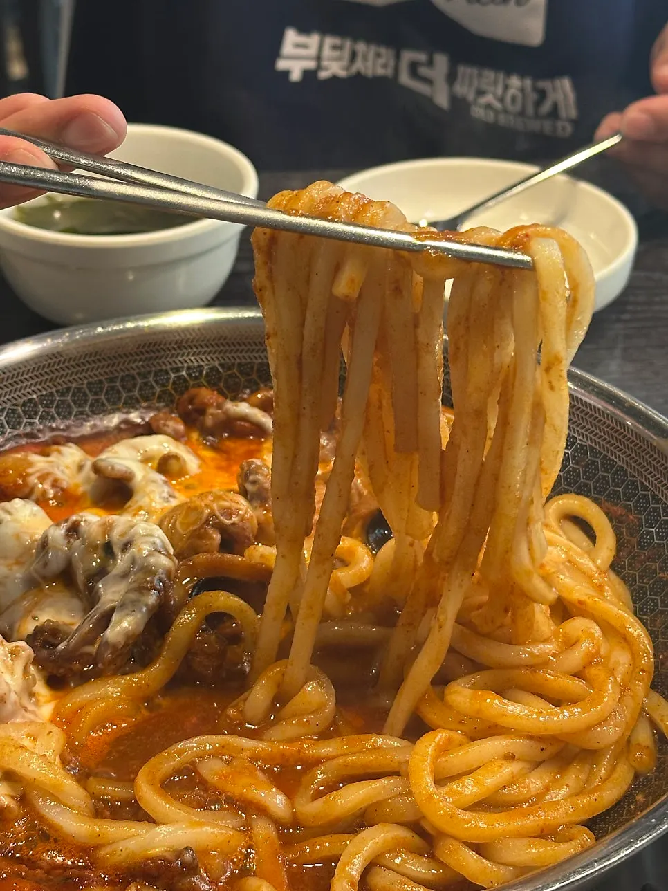 A chopstick-full of udon noodles coated in sauce