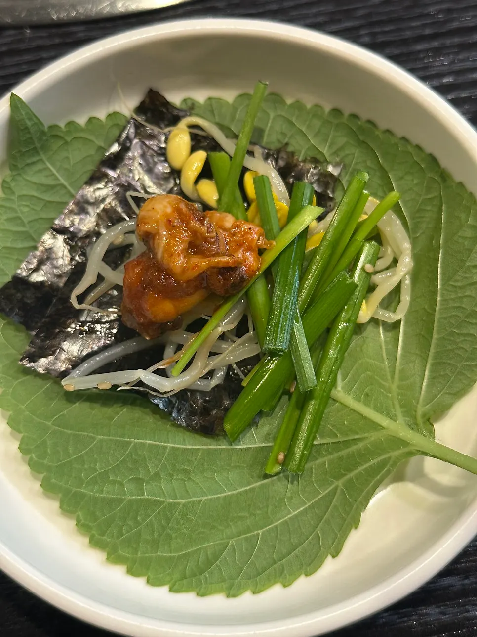 Wrap with perilla leaf and seaweed topped with bean sprouts, chives, and octopus