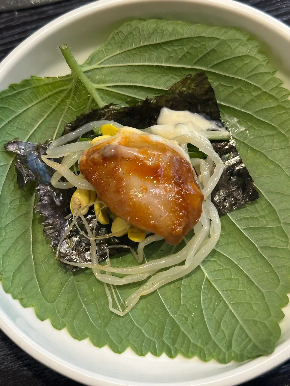 A wrap bite with perilla leaf, seaweed, bean sprouts, and octopus
