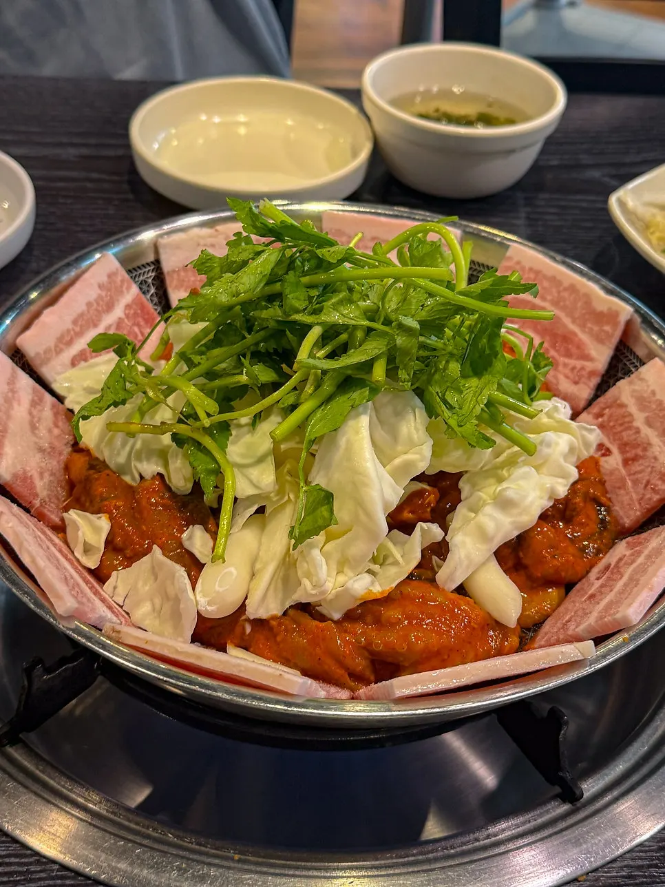 Grill pan with octopus flanked by pork belly and minari