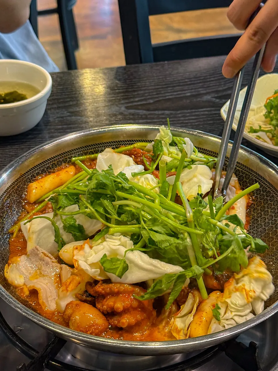 Staff member stir-frying the octopus and cabbage at the table