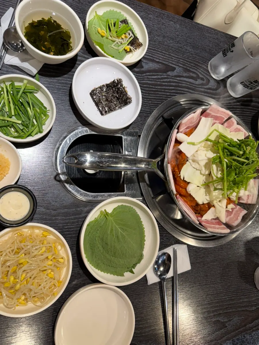 Side dishes including bean sprouts, perilla leaf, seaweed, and white kimchi