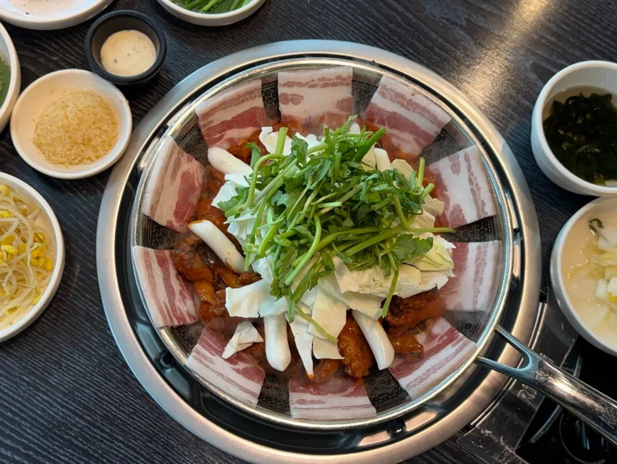 Pan of octopus and pork belly topped with rice cake and cheese rice cake