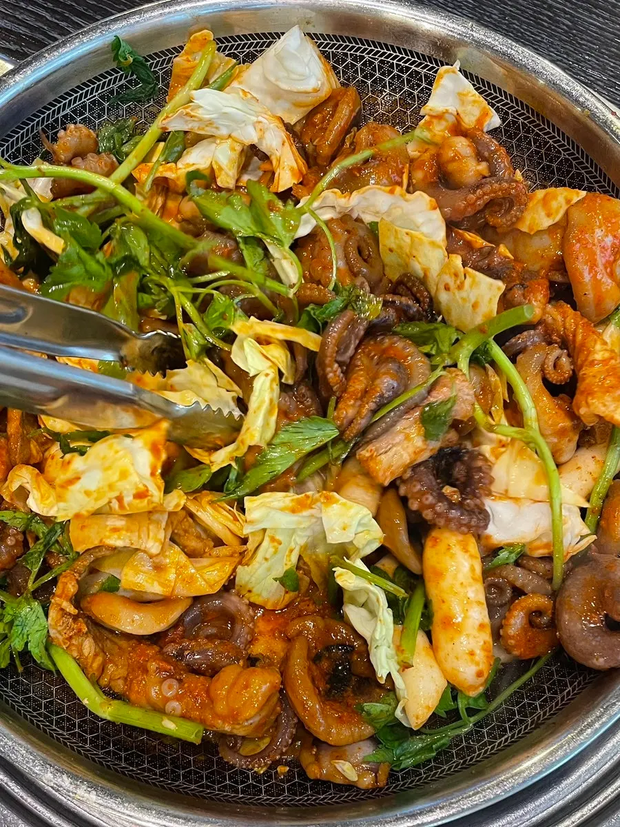 Pulpo y repollo cocinándose en la sartén de hierro