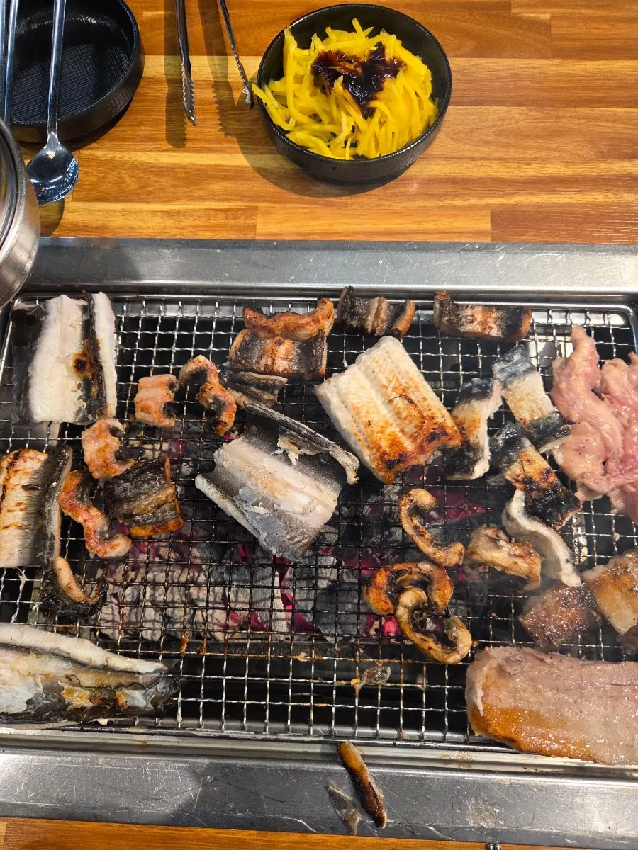 Eel and duck neck cooking together on the grill