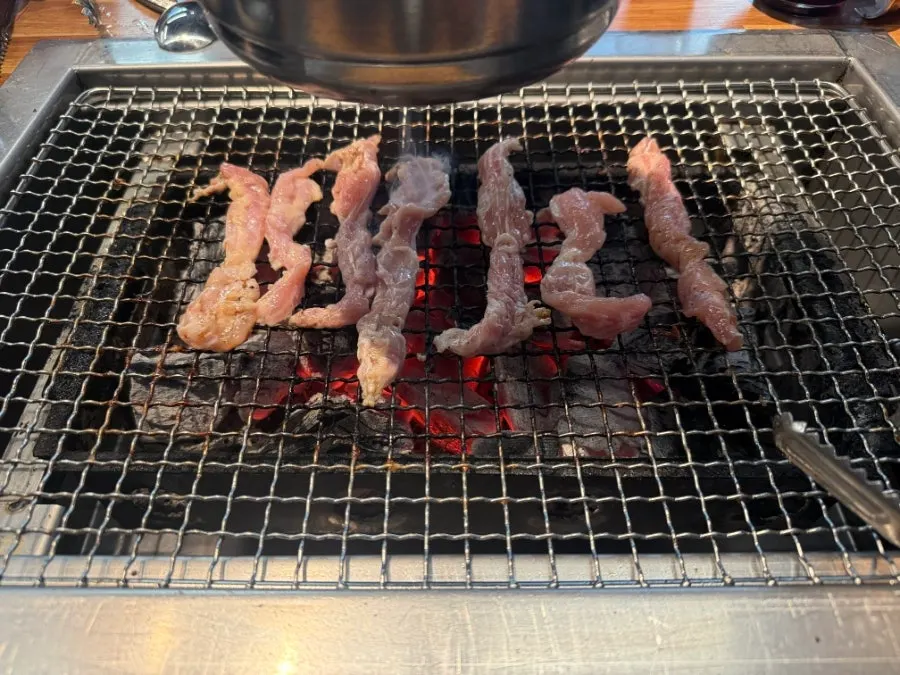 A piece of eel served with green onion kimchi and pickled onions