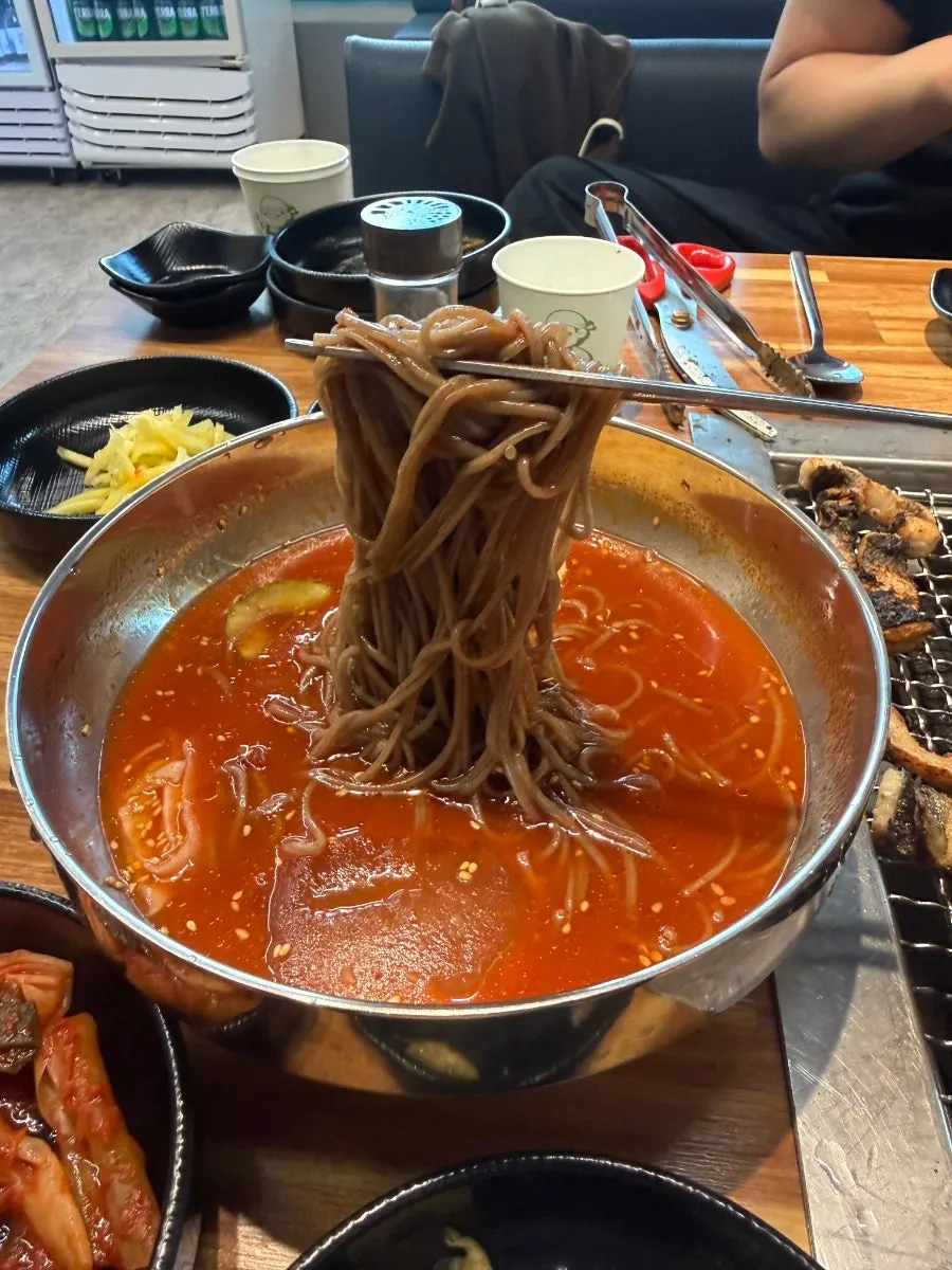 A bowl of buckwheat noodles with added seasoning sauce
