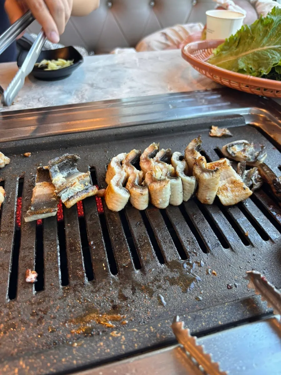 Eel grilling skin-side down alongside pork belly