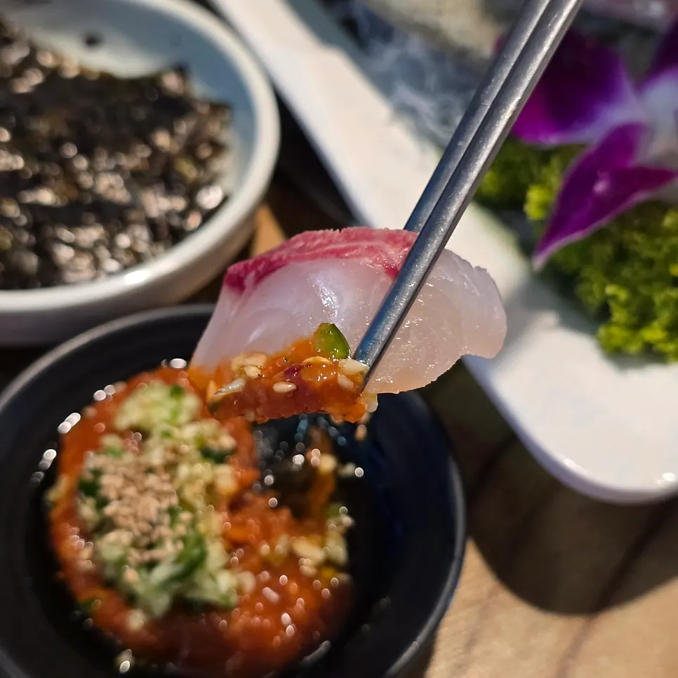 Picking up a piece of raw fish with chopsticks