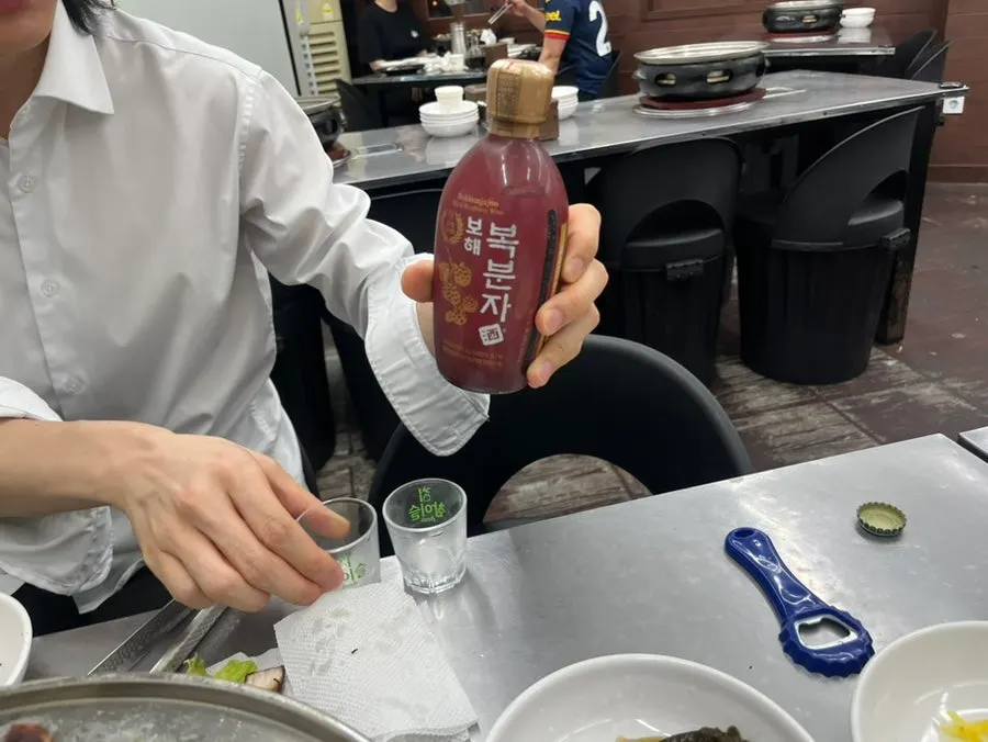 A glass of bokbunja served alongside the eel and meat