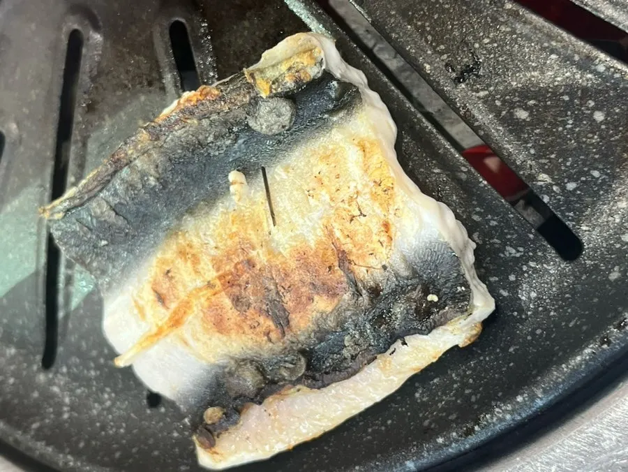 Pressing down on eel as it forms a ㅅ-shape while grilling