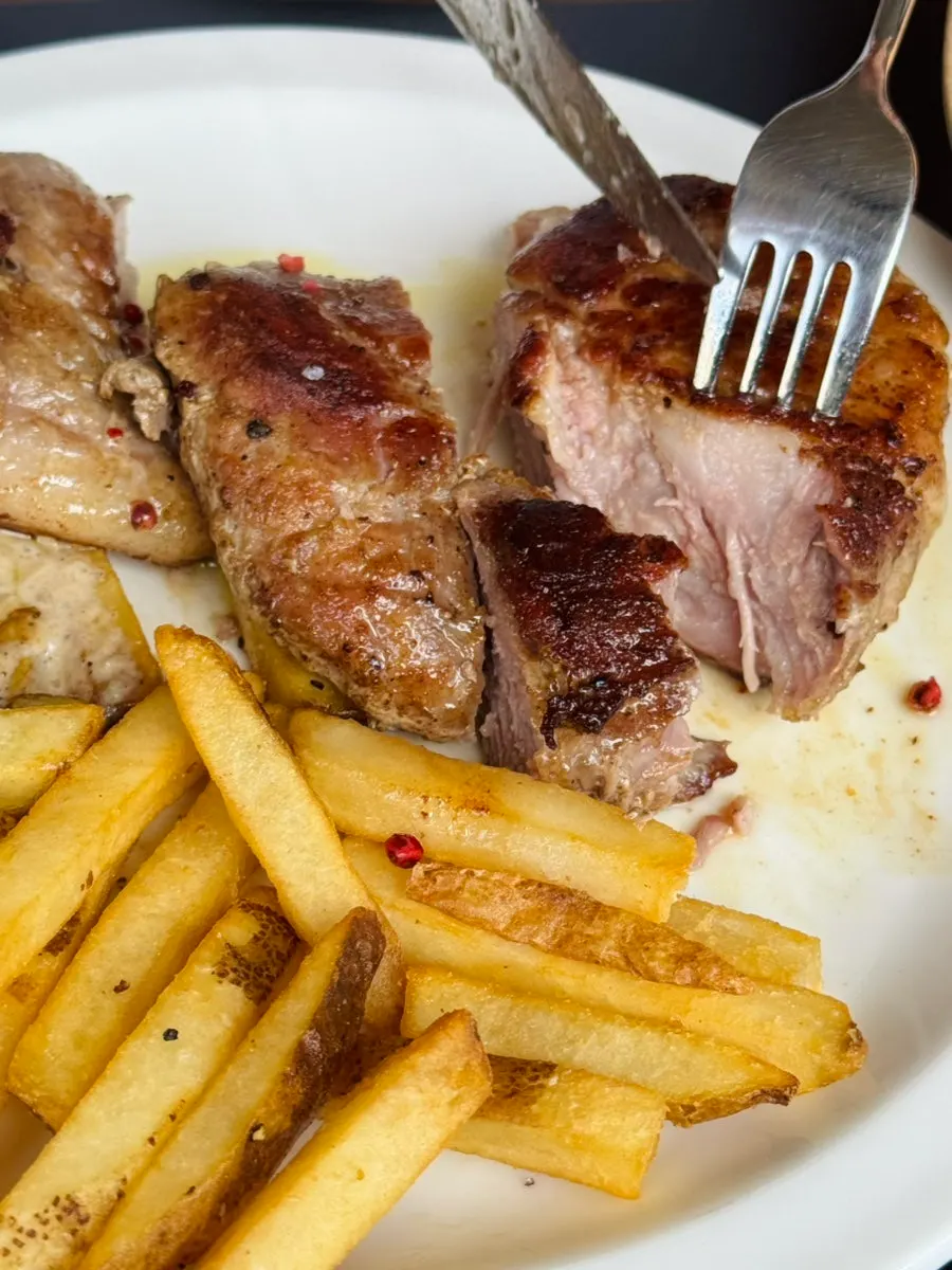 A piece of pork neck steak dipped in peppercorn sauce