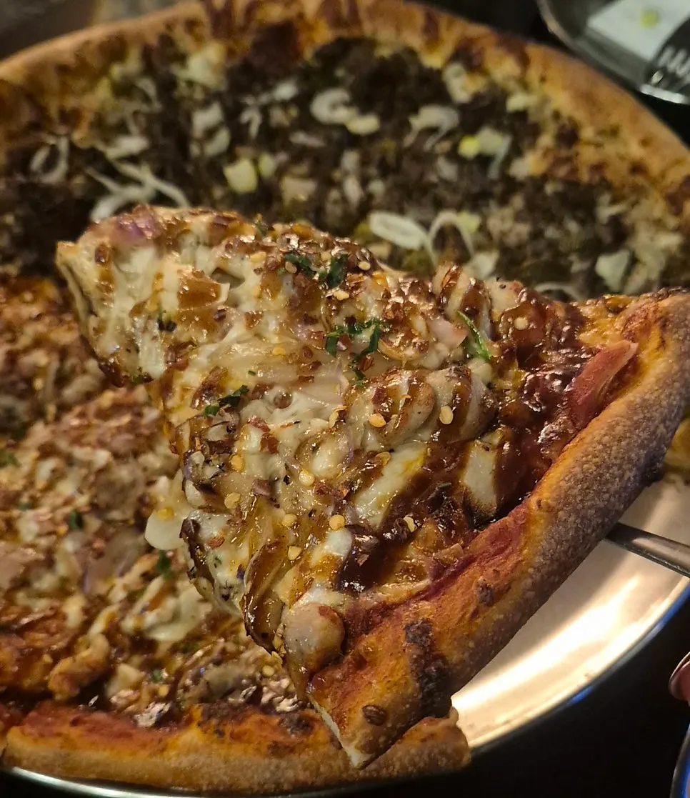 Slice of chicken pizza with cheese and sauce blended together