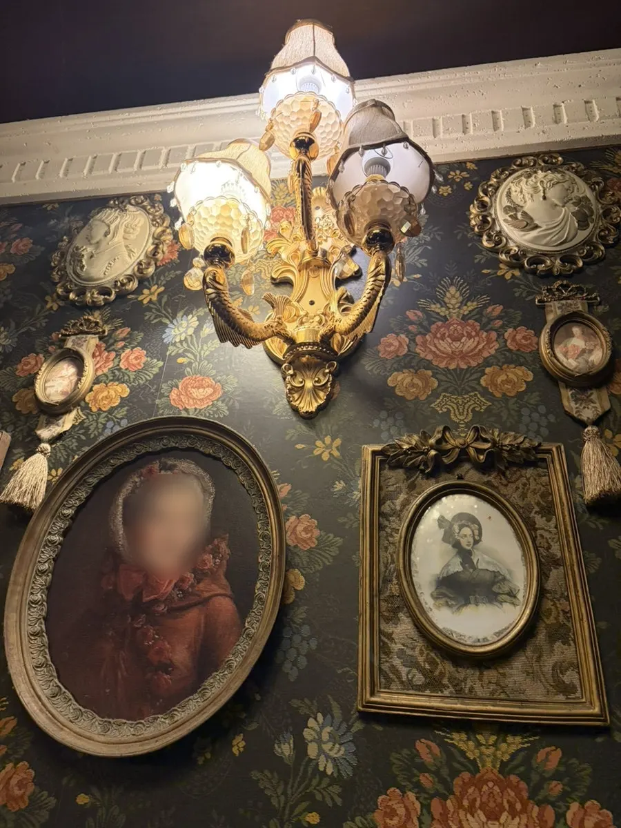 Wall with ornate wallpaper and antique frames