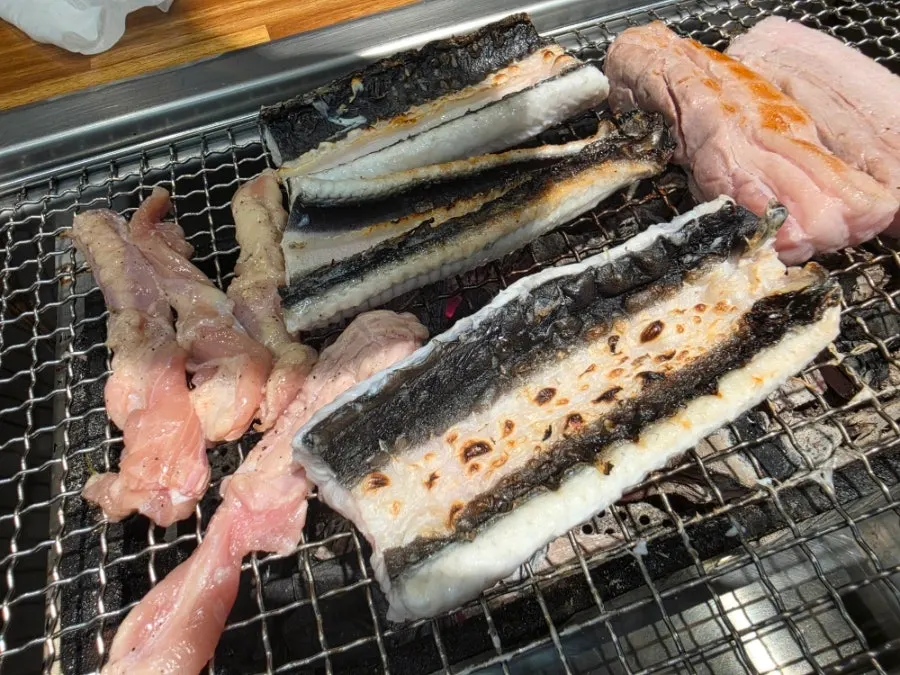 Pork belly and eel cooking on the charcoal grill