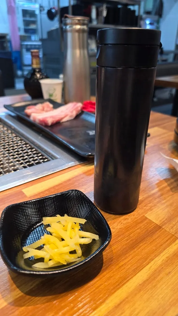 Eel sauce in a lidded tumbler alongside ginger