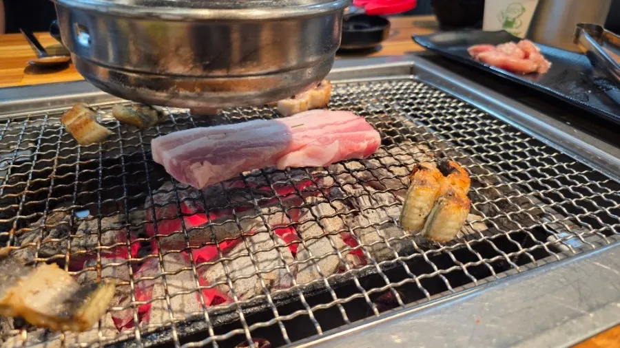 Pork belly grilling over charcoal