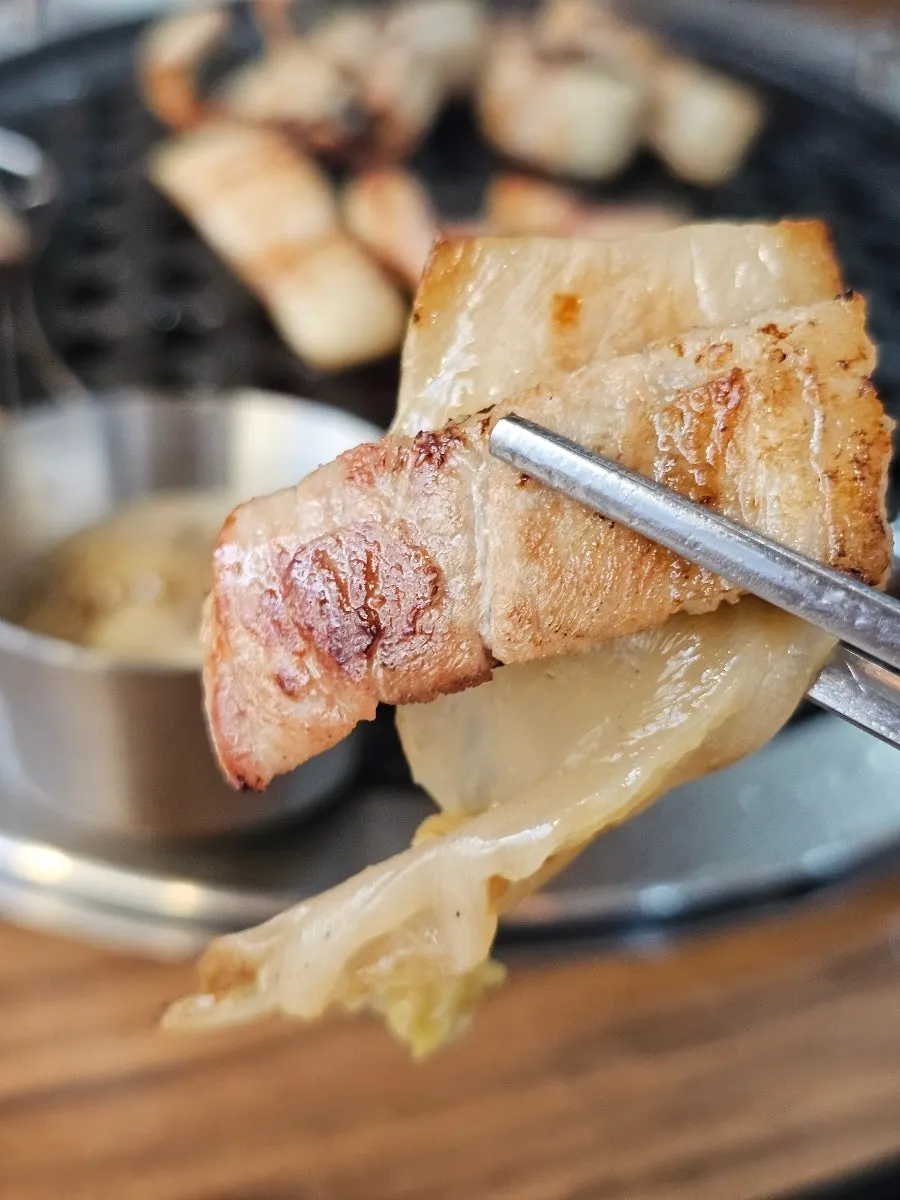 A grilled piece of pork belly ready to wrap in lettuce