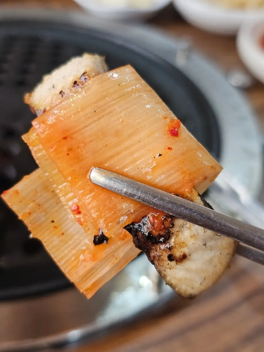 A piece of grilled eel topped with ginger