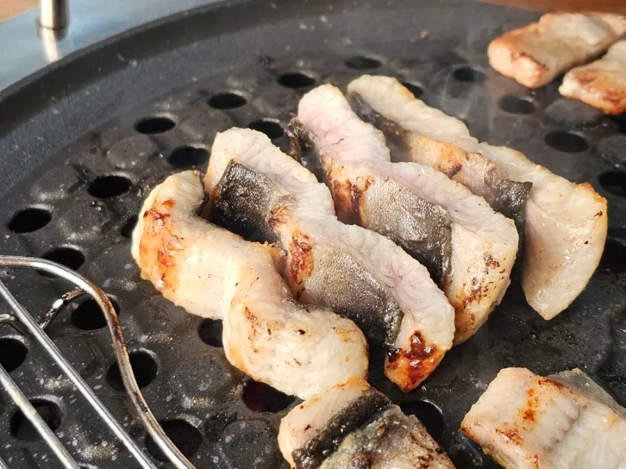 Eel, pork belly, and chicken neck meat grilling together on the plate