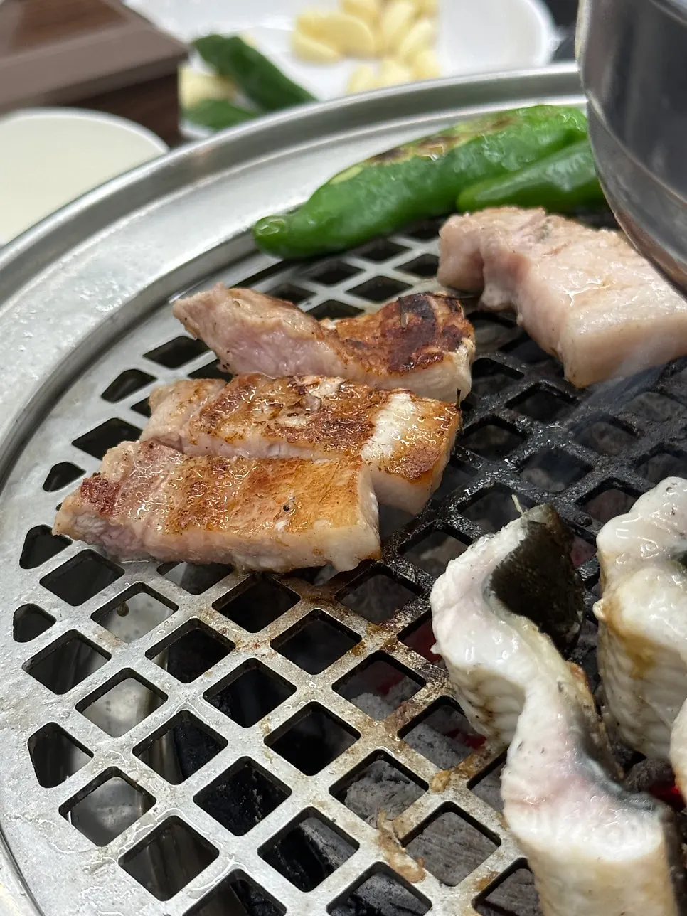 Pork belly grilling over charcoal