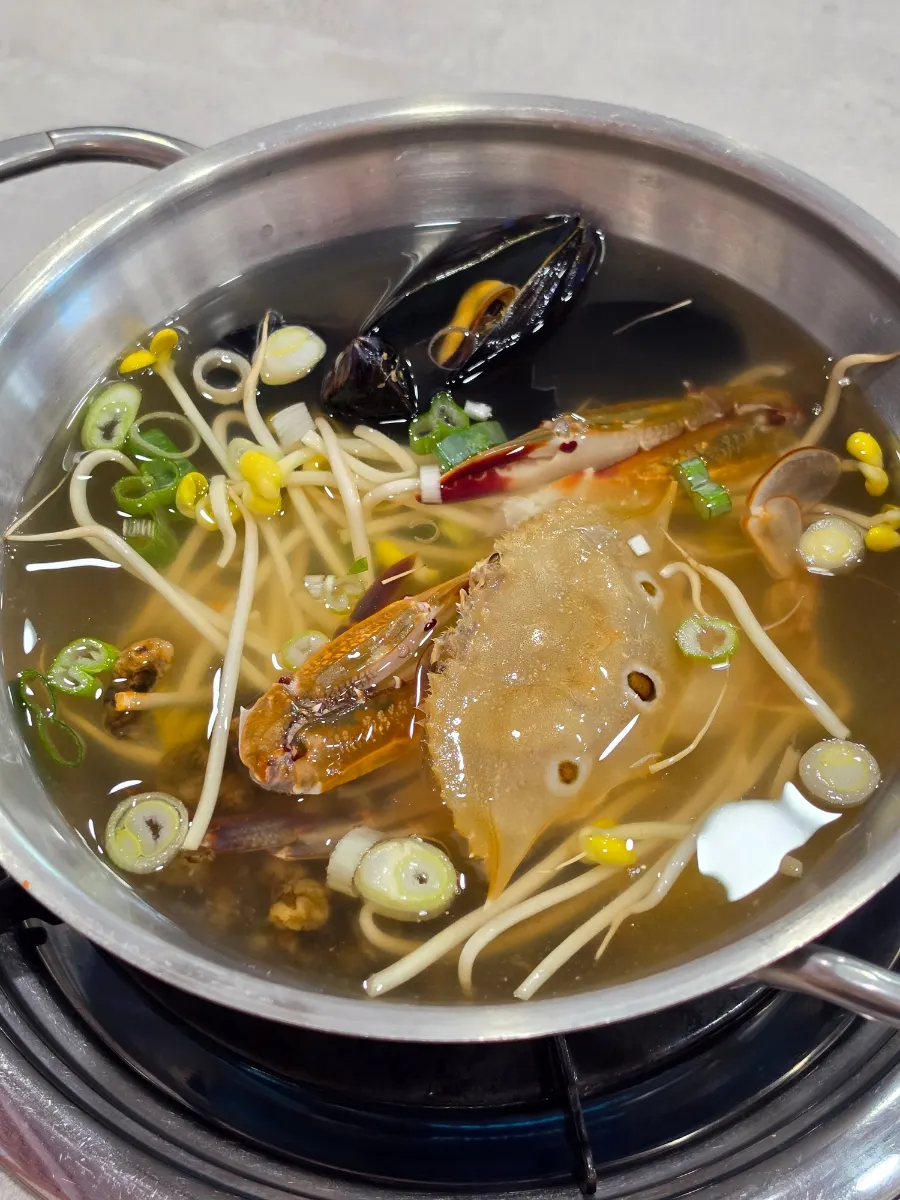 Pot of seafood kalguksu broth before boiling