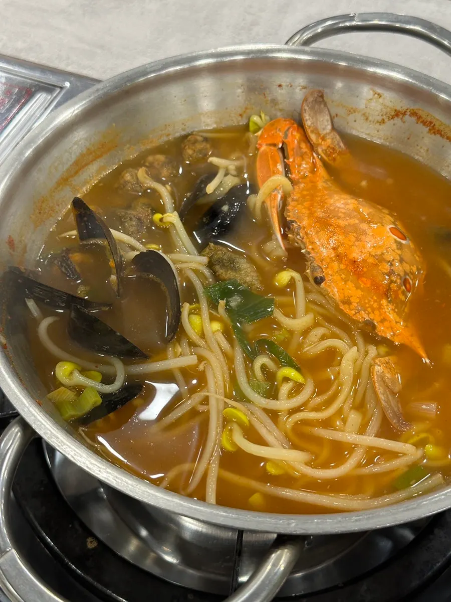 Seafood kalguksu broth with chili paste added
