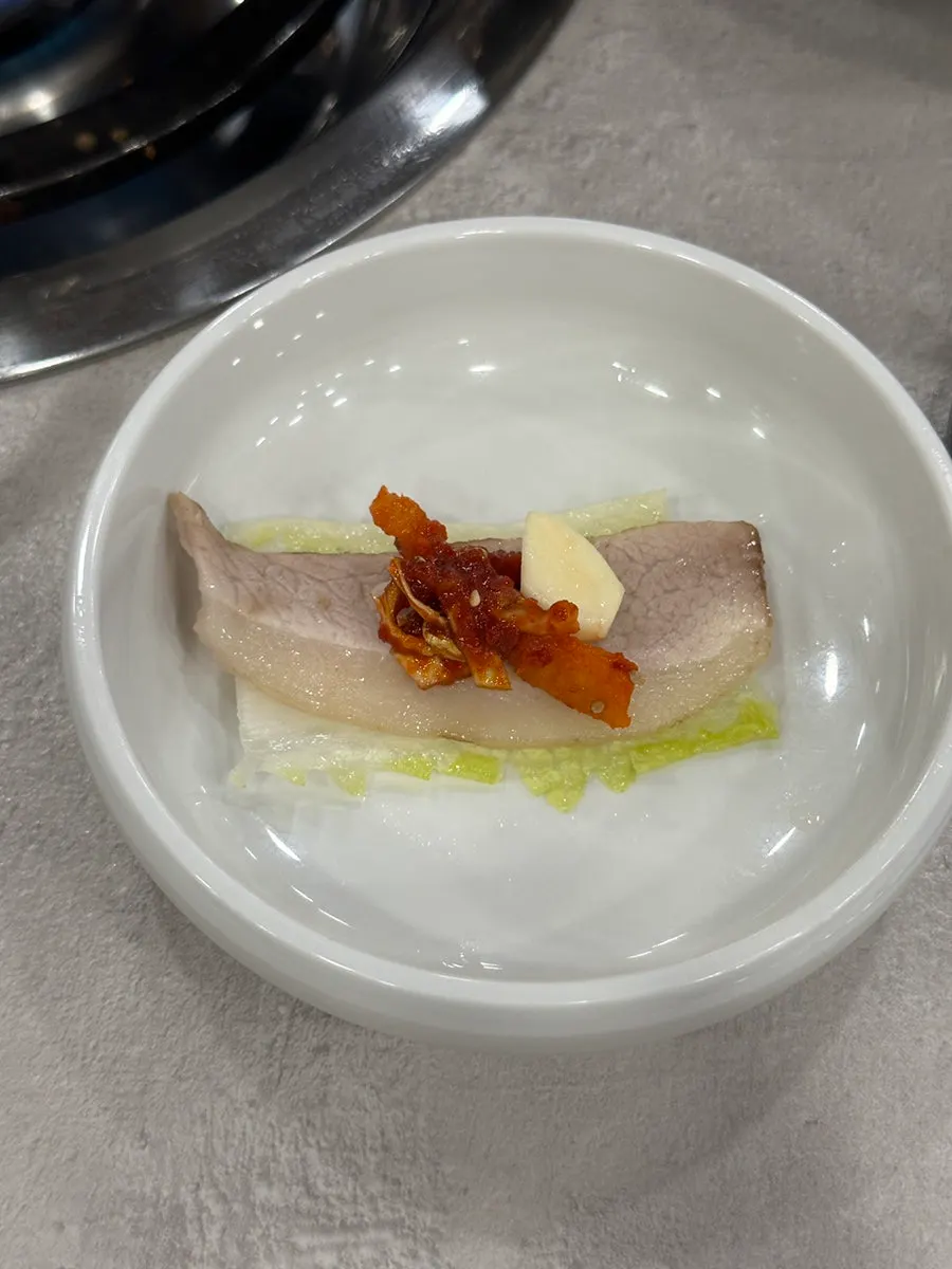 A piece of gabrisal bossam with kimchi filling and radish kimchi