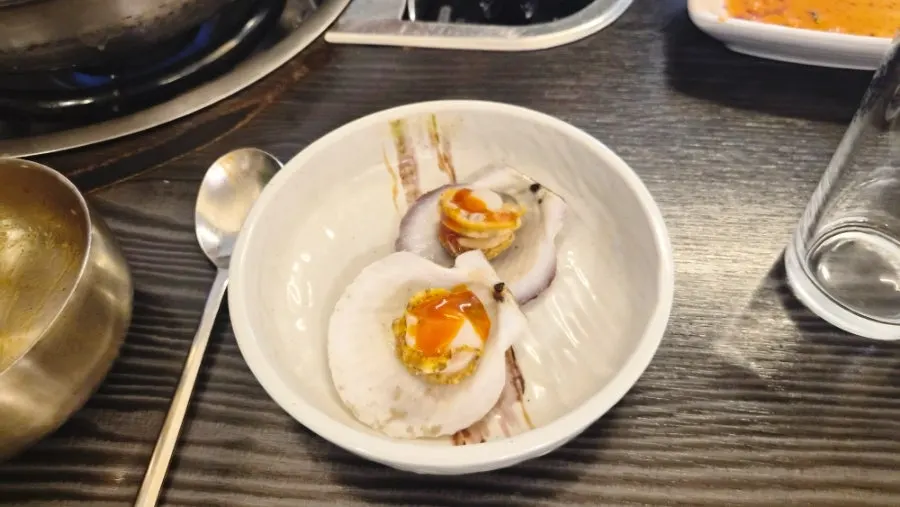 Pot of seafood kalguksu with seafood being pulled out