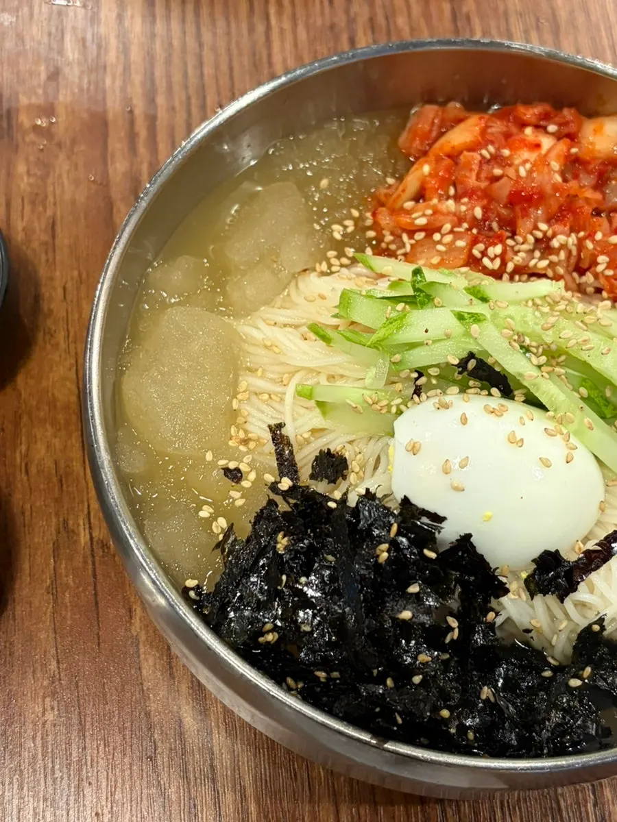 A bite of meat wrapped with ssamjang and minari