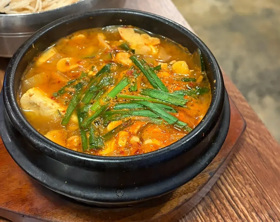 A bowl of kimchi mari guksu with floating ice cubes