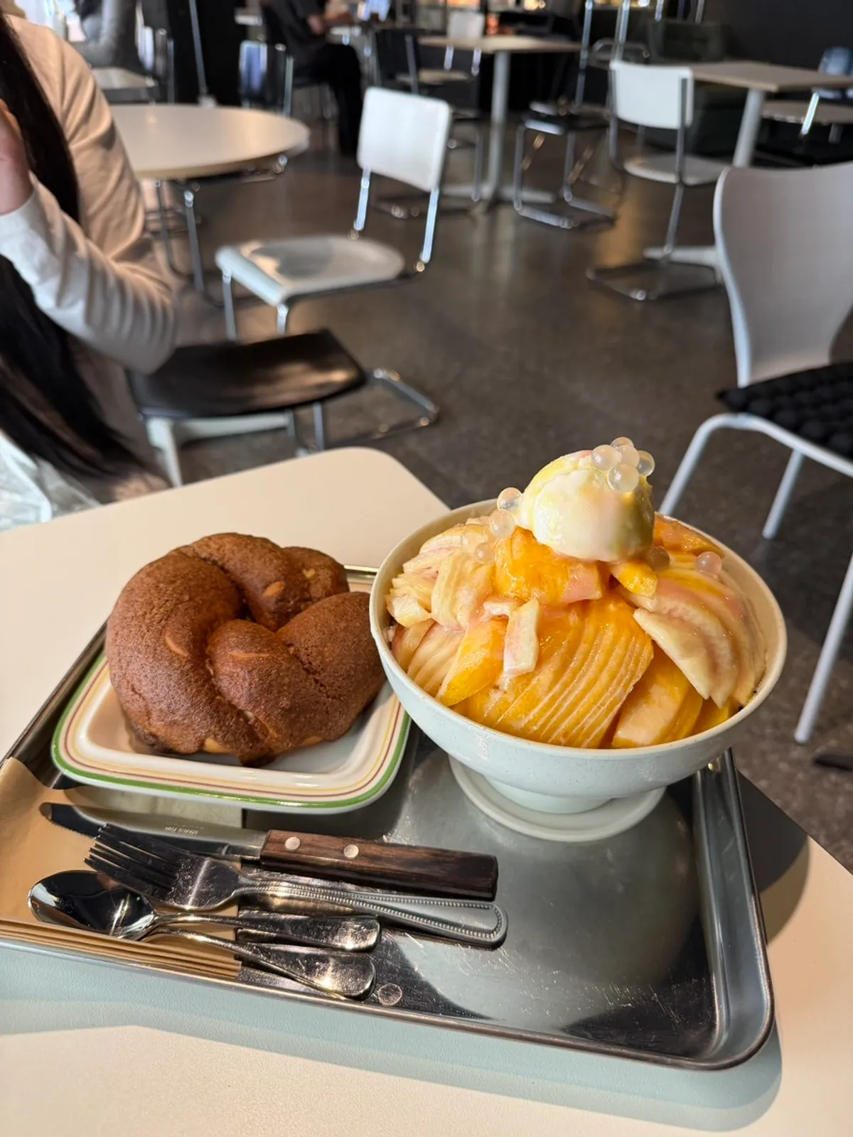 Peach bingsu piled high with peaches, next to a mocha bagel