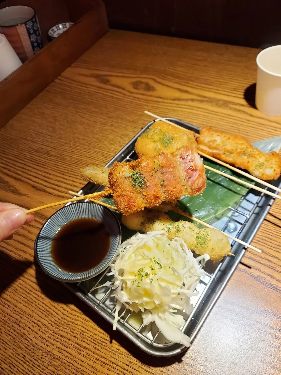 A plate of assorted kushikatsu including quail egg, sausage, and lotus root