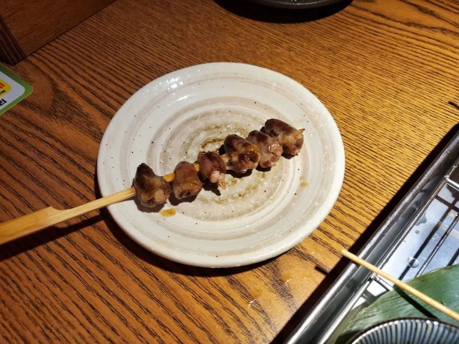 A plate of chicken skin skewers with a charcoal aroma