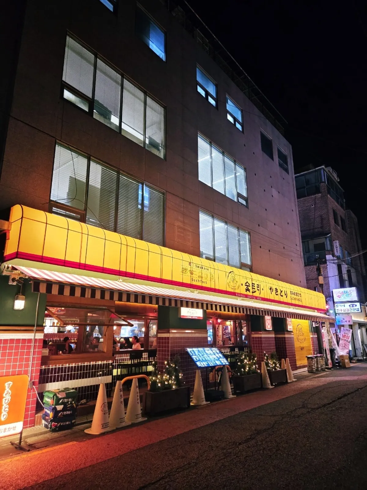 Night view of Soottori Hongdae Hapjeong's yellow exterior with red accents