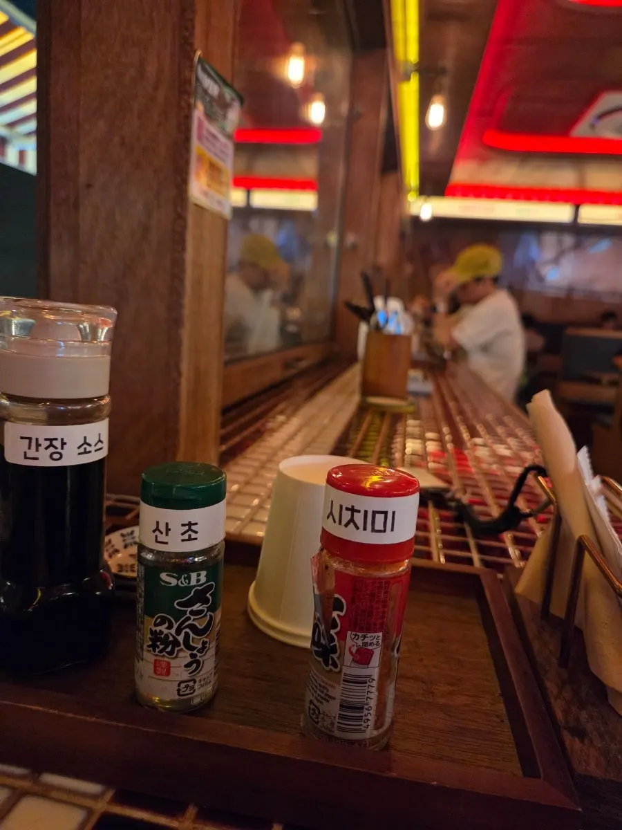 Table setting with soy sauce, sansho pepper, and shichimi